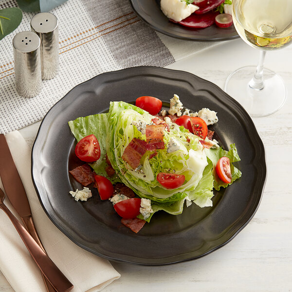 A plate of salad with tomatoes and blue cheese on an Acopa Condesa scalloped wide rim porcelain plate.