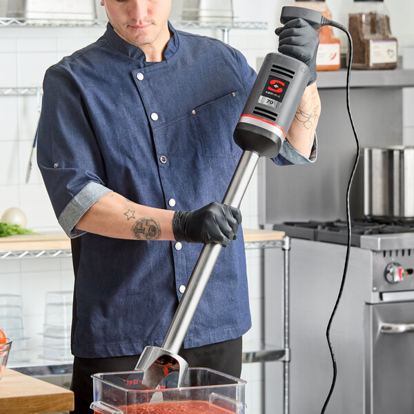 A heavy-duty Sammic XM-72 immersion blender with a long shaft being used to blend ingredients in a commercial kitchen.
