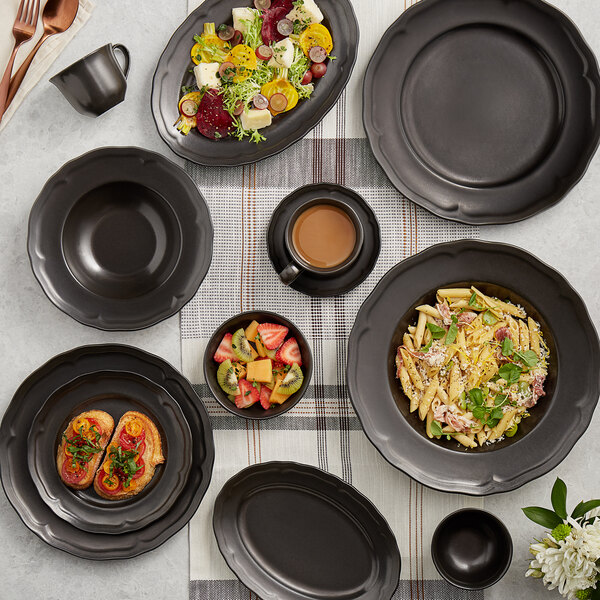 An Acopa Condesa matte gray porcelain saucer on a table with plates of food and coffee.