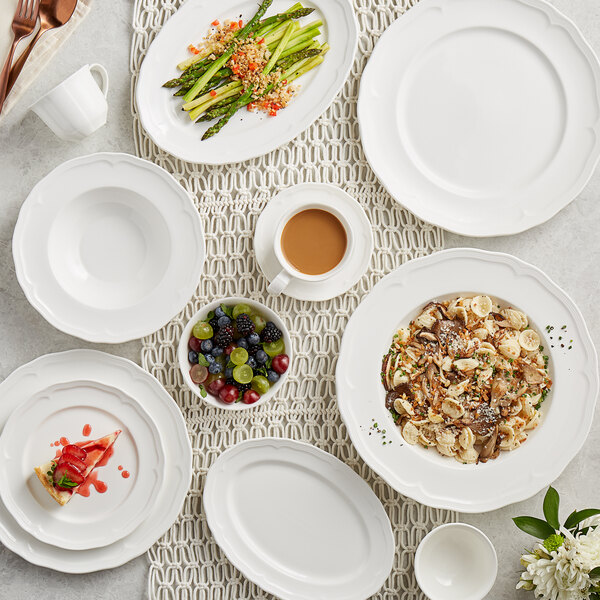 A table with Acopa Condesa pearl white plates, bowls, and cups on it.