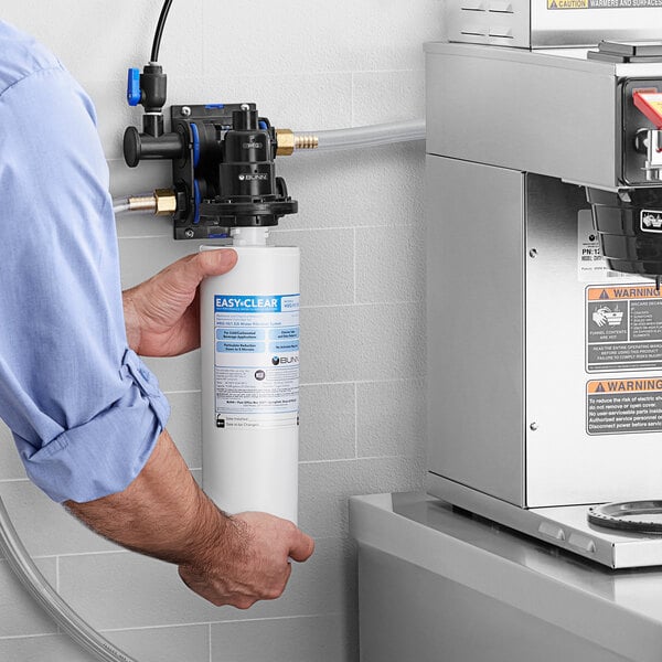 A man holding a white cylinder water filter.