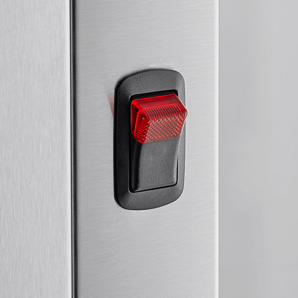 A close-up of a red light on a metal switch on a ServIt chip warmer.