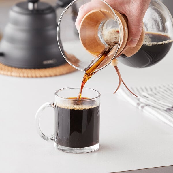 A person pouring Arrosto Ethiopia Yirgacheffe whole bean coffee into a glass jar.