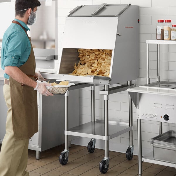 A man wearing gloves and an apron fills a ServIt chip warmer.