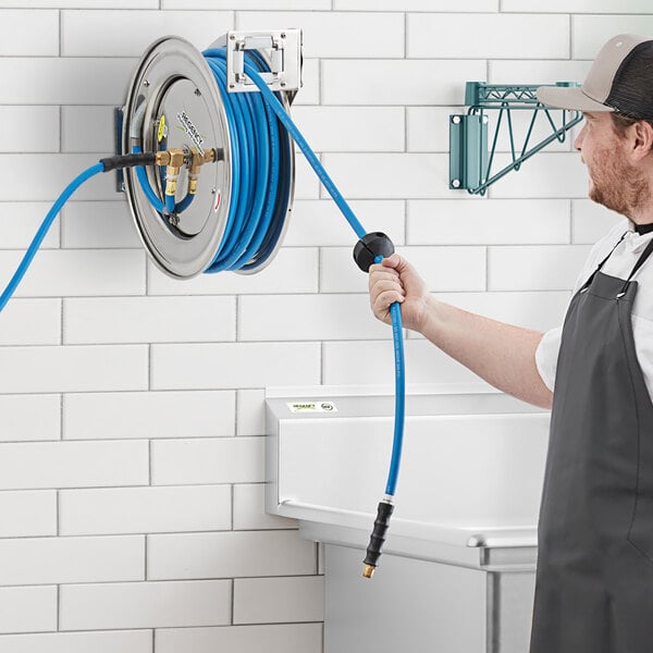 A man holding a stainless steel hose reel with a blue hose.