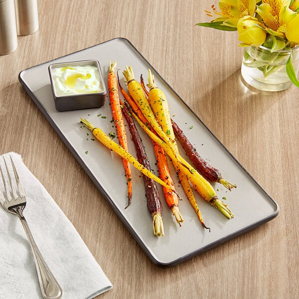 A rectangular melamine tray with colorful carrots and sauce on it.