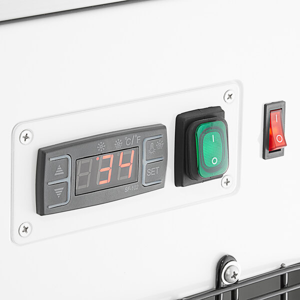 A control panel with a digital temperature display, green power switch, and red on/off switch on a refrigerated bakery display case.