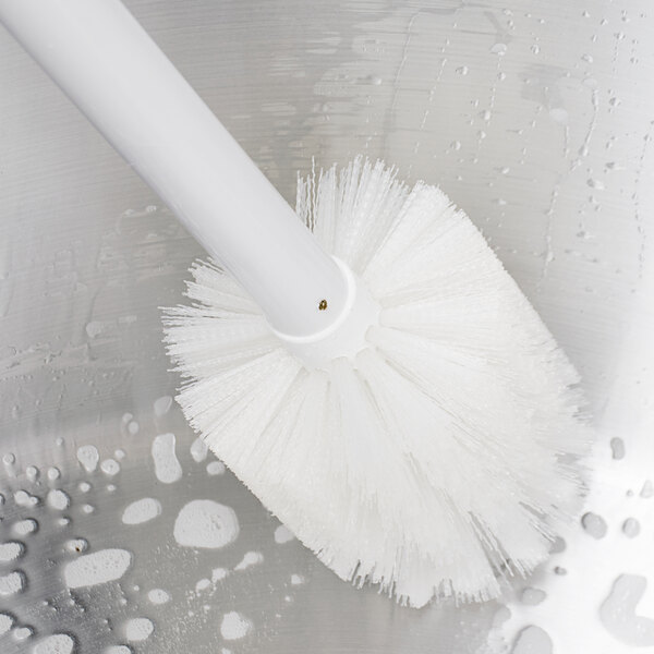 A close-up of a Carlisle white multi-purpose cleaning brush with a handle.