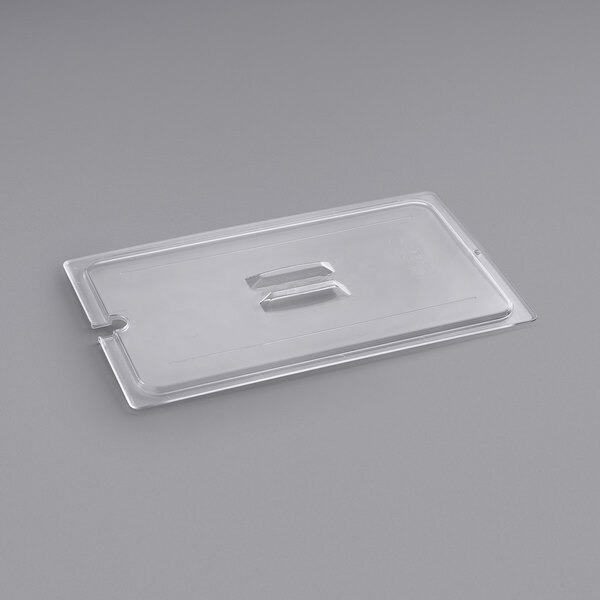 A clear plastic Cambro lid with a spoon notch over a food container.