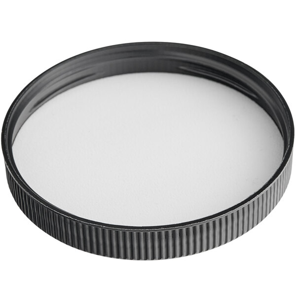 A black ribbed plastic cap with a foam liner over a white surface.