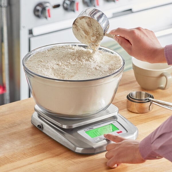 A stainless steel digital kitchen scale with an extra large platform, displaying a bowl of flour being measured.