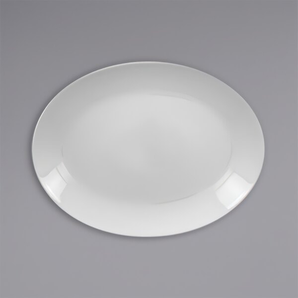 A white RAK Porcelain oval coupe platter with a white rim on a gray surface.