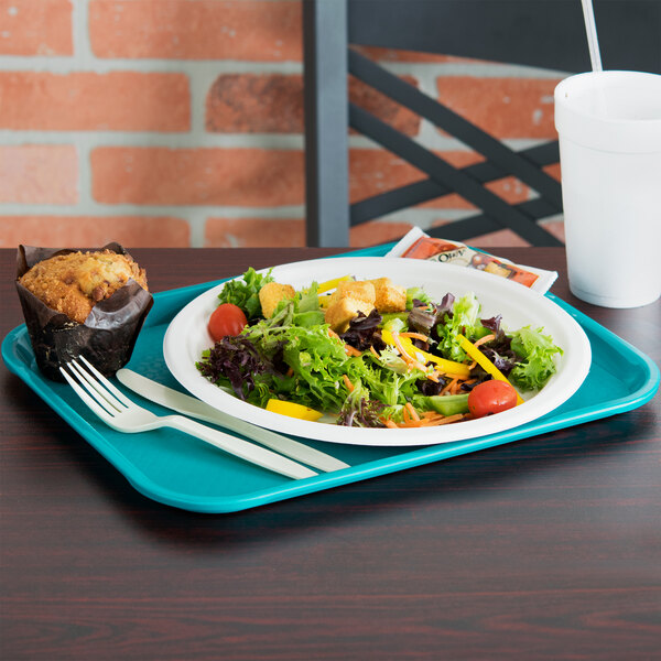 A white tray with a salad and muffin on it.