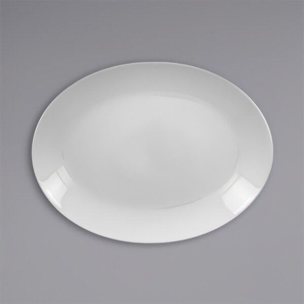 A white porcelain oval coupe platter with a white rim on a gray surface.