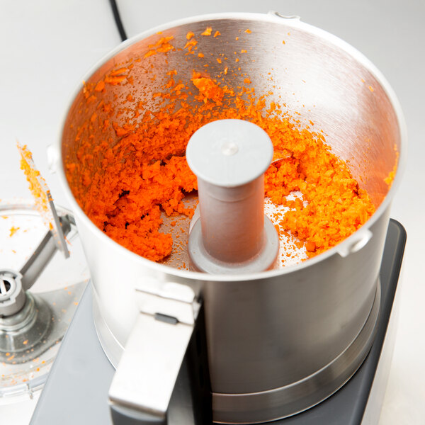 A Robot Coupe stainless steel bowl full of orange food.