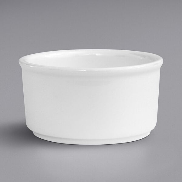 A Fortessa Fortaluxe white porcelain ramekin on a gray surface.