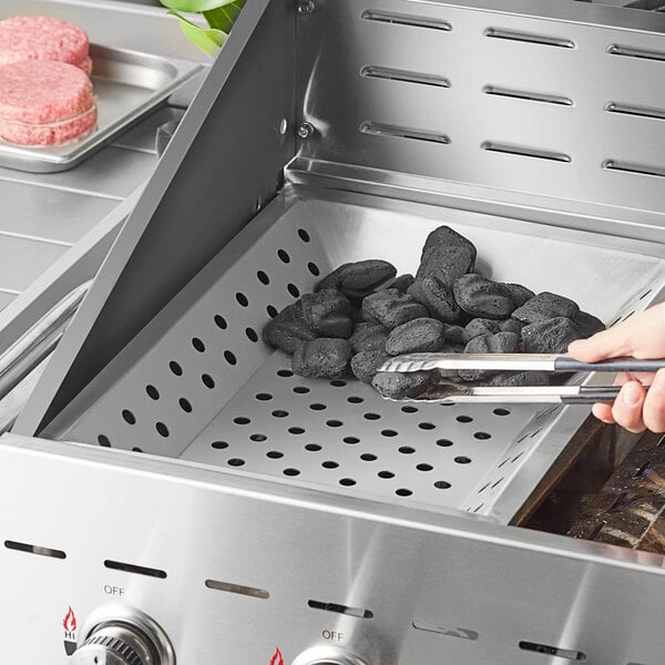 A person using tongs to cook meat on a grill with a Backyard Pro Charcoal Tray.