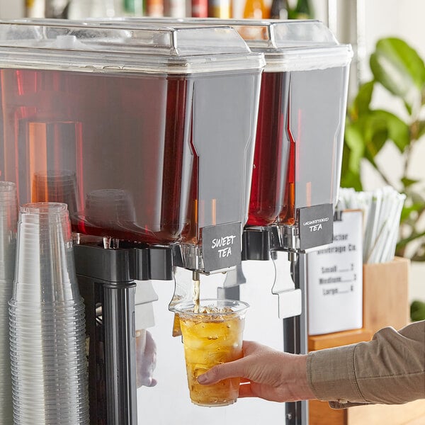 A person pouring Tractor Beverage Co. Organic Sweet Tea concentrate into a cup.
