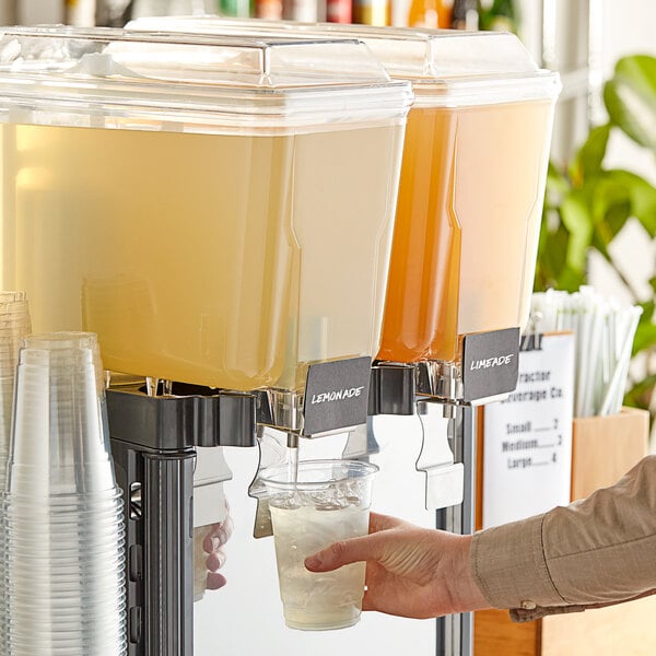 A person pouring Tractor Beverage Co. organic lemonade concentrate into a juice dispenser.