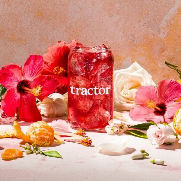 A glass of Tractor Beverage Co. Hibiscus drink with flowers on the side.