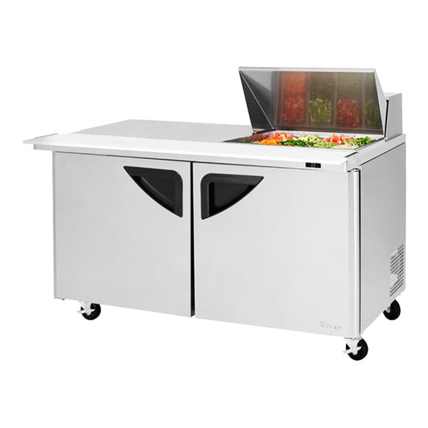 A Turbo Air stainless steel 2 door refrigerated sandwich prep table with a glass door on top of a counter.