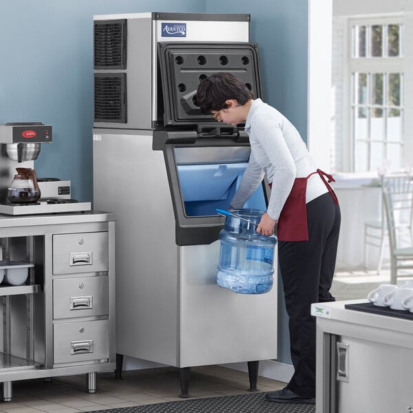 A man using an Avantco air cooled ice machine to fill a container with ice.