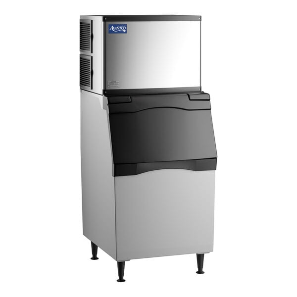 A freestanding, rectangular stainless steel and black appliance with a top-mounted vented unit and a large front bin, standing on four legs.