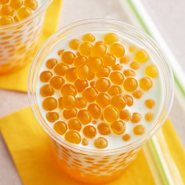 A close-up of a cup of bubble tea with milk and Fanale passion fruit popping boba.