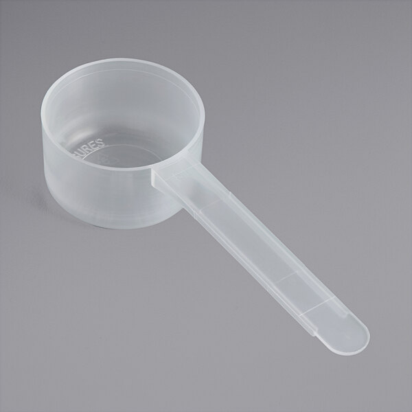 A clear plastic measuring scoop with a long handle.