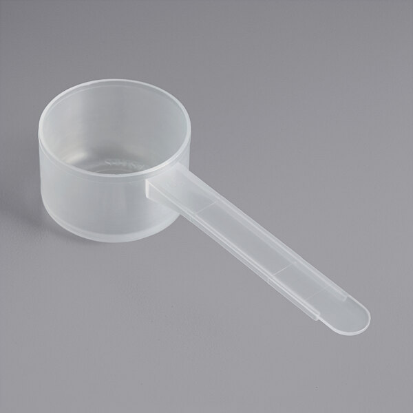 A clear plastic measuring scoop with a long handle.