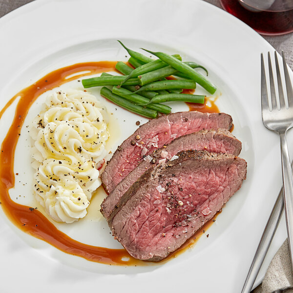 A plate of Shaffer Venison Farms venison roast, mashed potatoes, and gravy with a fork and knife.