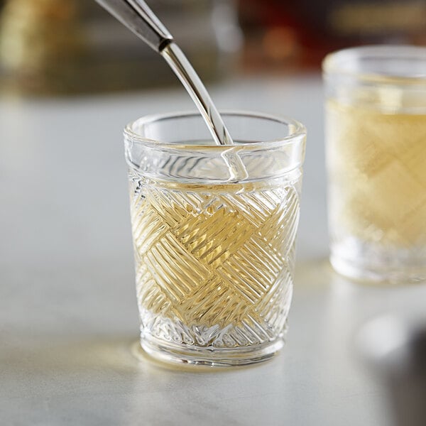 A close-up of an Acopa Zion shot glass with liquid being poured into it.