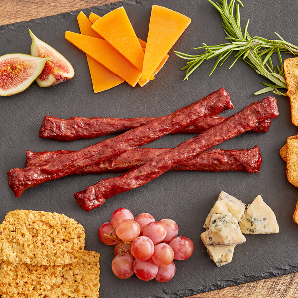 A platter with cheese, crackers, grapes and Shaffer Venison Farms Teriyaki Venison Snack Sticks on a table.