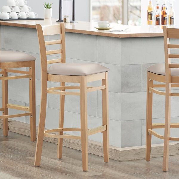 A Lancaster Table & Seating light gray vinyl seat for a wooden chair.