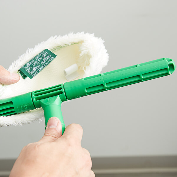 A hand holding a green Unger Original StripWasher Sleeve.