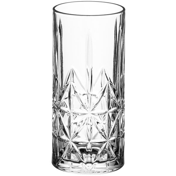 A close-up of an Acopa Gardenia clear beverage glass with a star pattern.