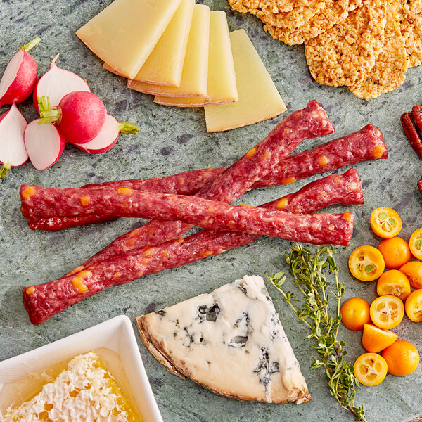 A plate with Shaffer Venison Farms venison and cheddar snack sticks and cheese slices on a table.