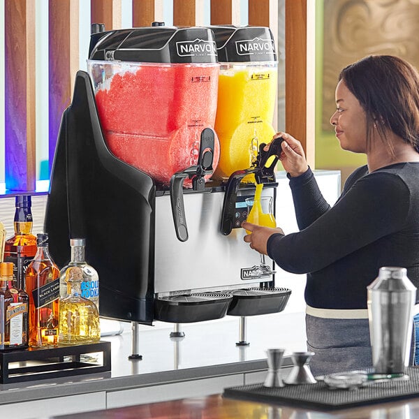 A woman using a Narvon machine to make a slushy drink.