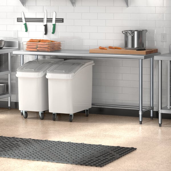 A Steelton stainless steel work table in a kitchen with two white bins.