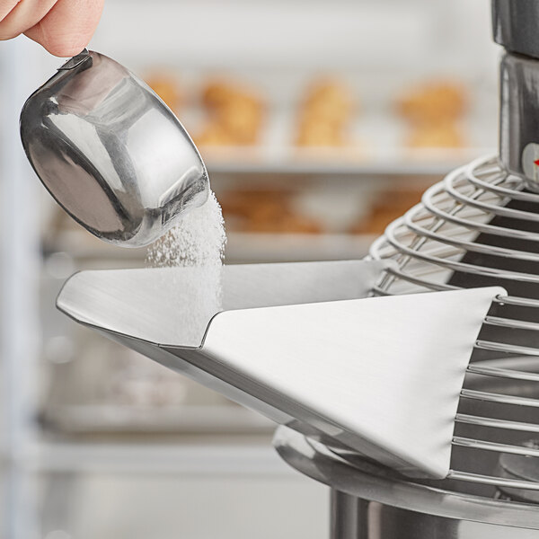 A person using an Avantco ingredient chute to pour salt into a food mixer.