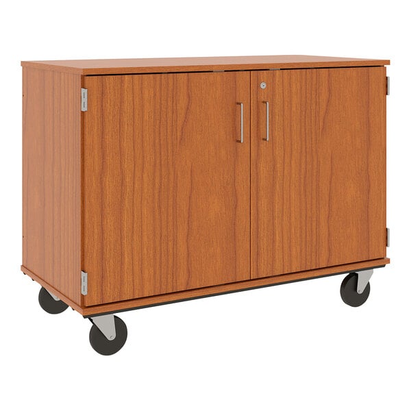 A medium cherry wooden cabinet on wheels with two metal doors and two drawers.