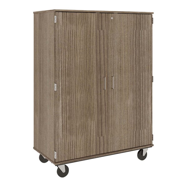 A brown wooden I.D. Systems cabinet with two doors on wheels.