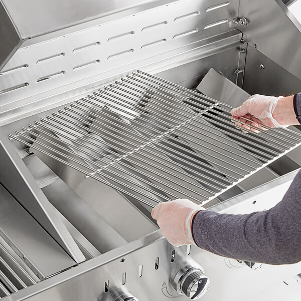 A person holding a Backyard Pro metal grill grate.