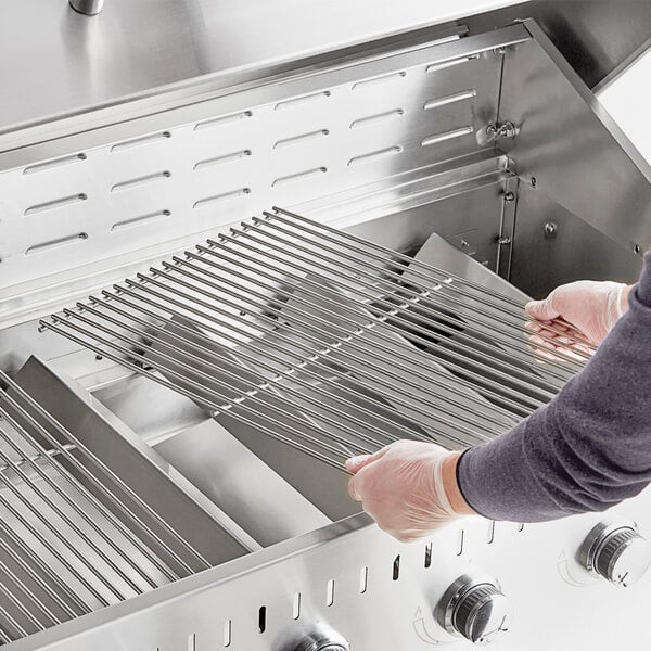 A person using a Backyard Pro grill cooking grate to cook food on a grill.