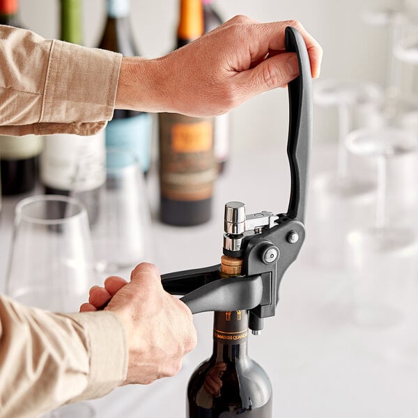 Person using a lever corkscrew to uncork a wine bottle