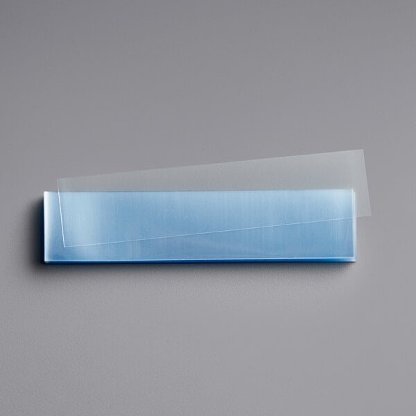 A clear rectangular plastic band with a blue piece inside.