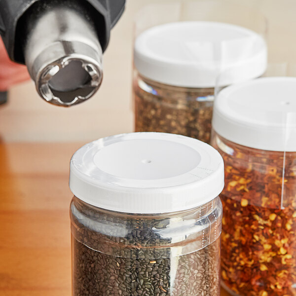 A close-up of a jar with a clear perforated shrink band on a white lid.
