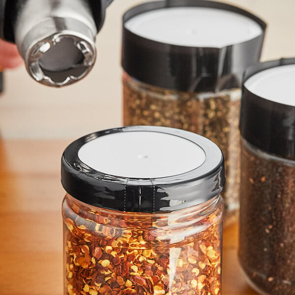 A jar of spices with a black shrink band on a counter.