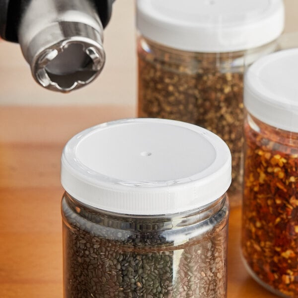 A clear shrink band on a jar of seeds with a white lid.