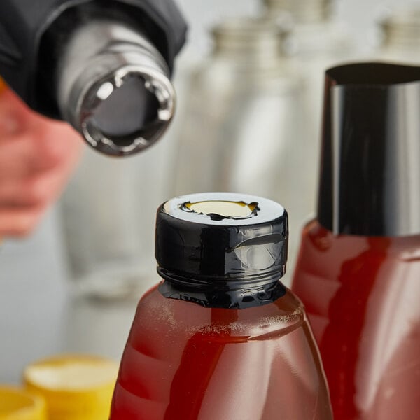 A close up of a 2" black non-perforated shrink band on a yellow bottle.